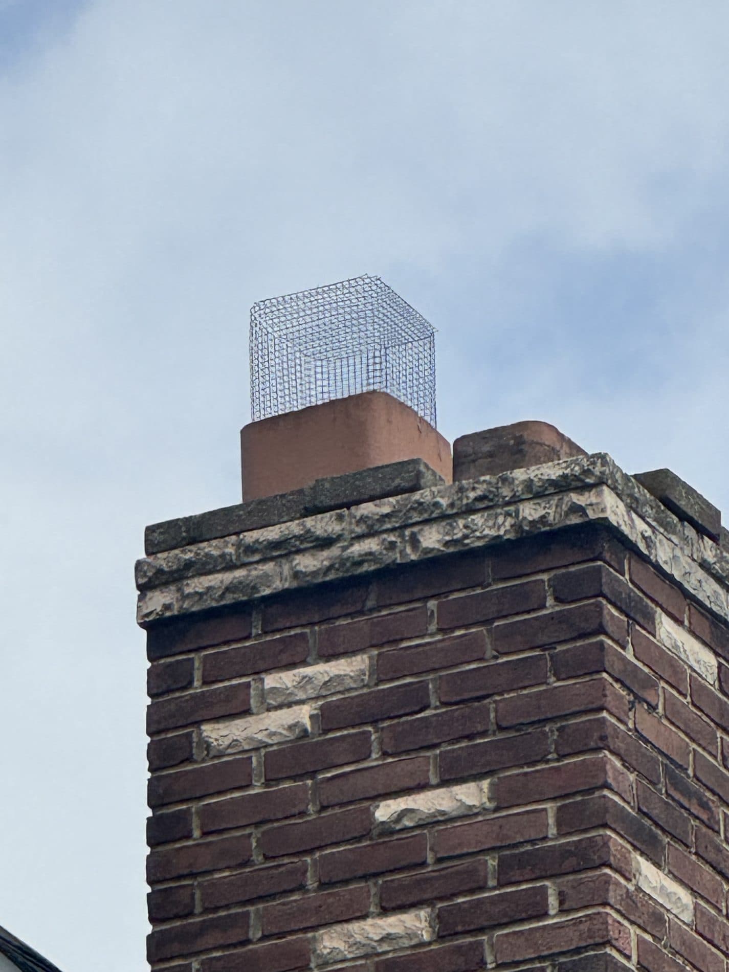 Rebuilt chimney in dark brick with recessed accent bricks and a rock-faced stone crown course