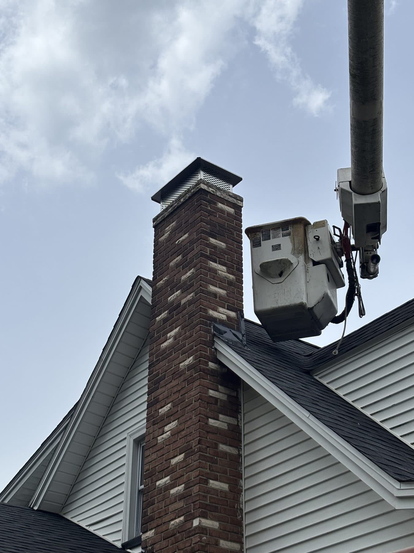 HydroGuard bucket truck reaching a tall brick chimney for repointing