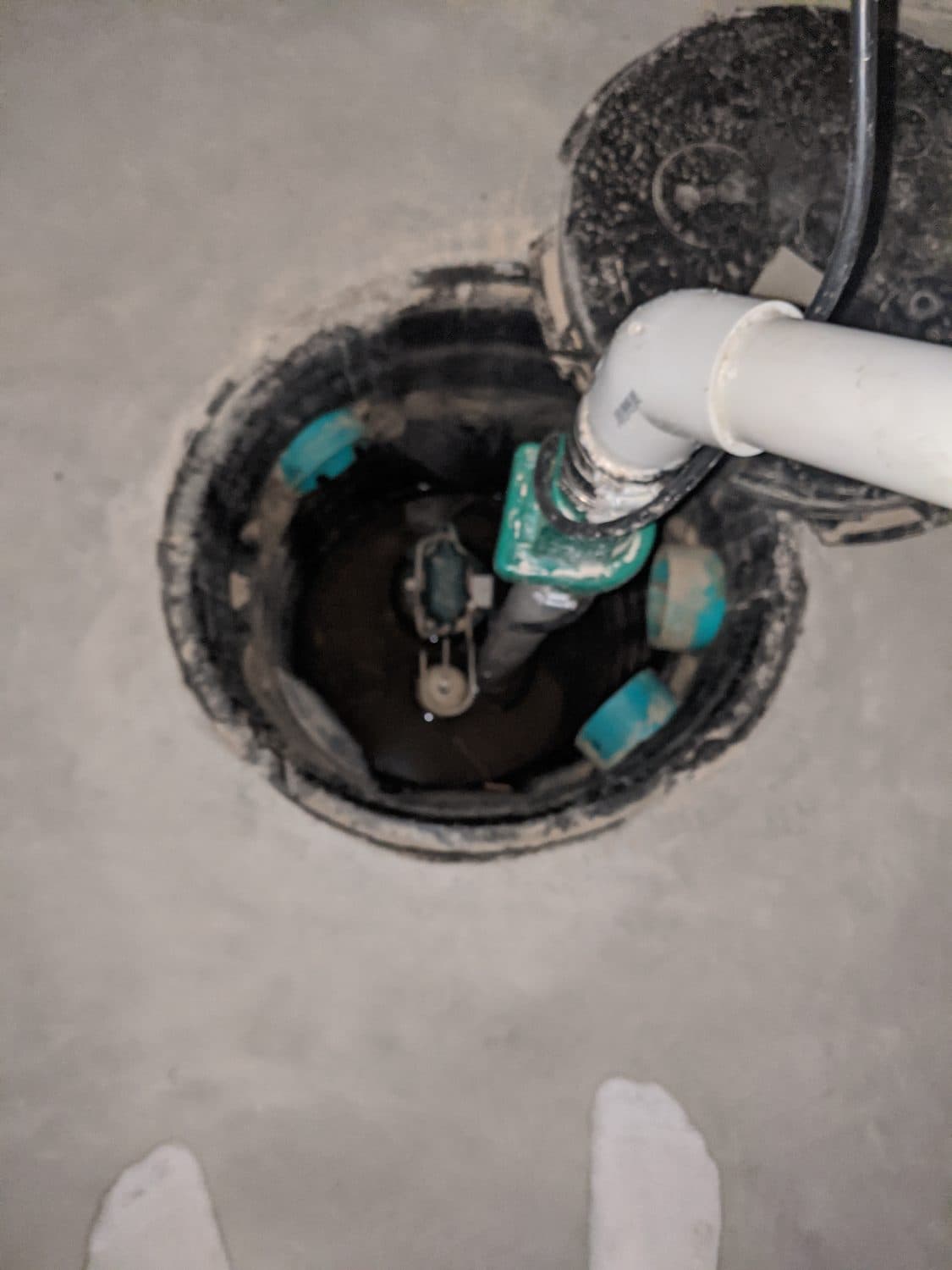 New sump pump set in a basement pit with float switch and discharge line